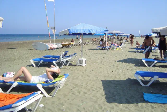 Het Faros-strand bij Pervolia met ligbedden en parasols op het beige zand
